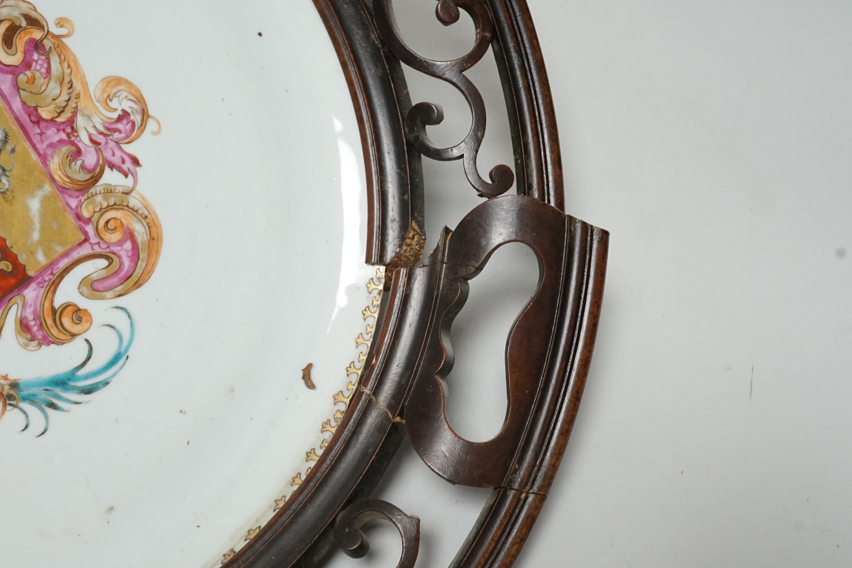 An 18th century Chinese armorial dish, rim cut down and mounted in a 19th century English mahogany frame, 39cm diameter